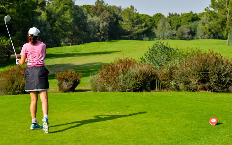 Golfeuse sur le départ d'un parcours verdoyant et arboré