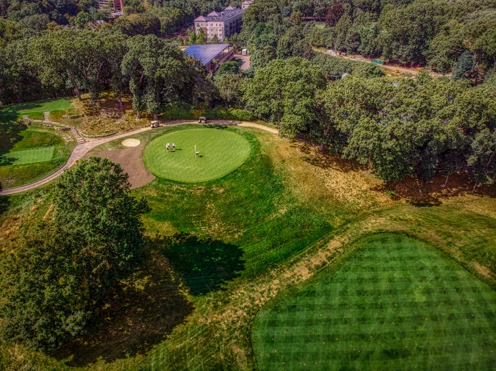 Vue aérienne d'un parcours de golf entouré d'arbres sous un ciel ensoleillé